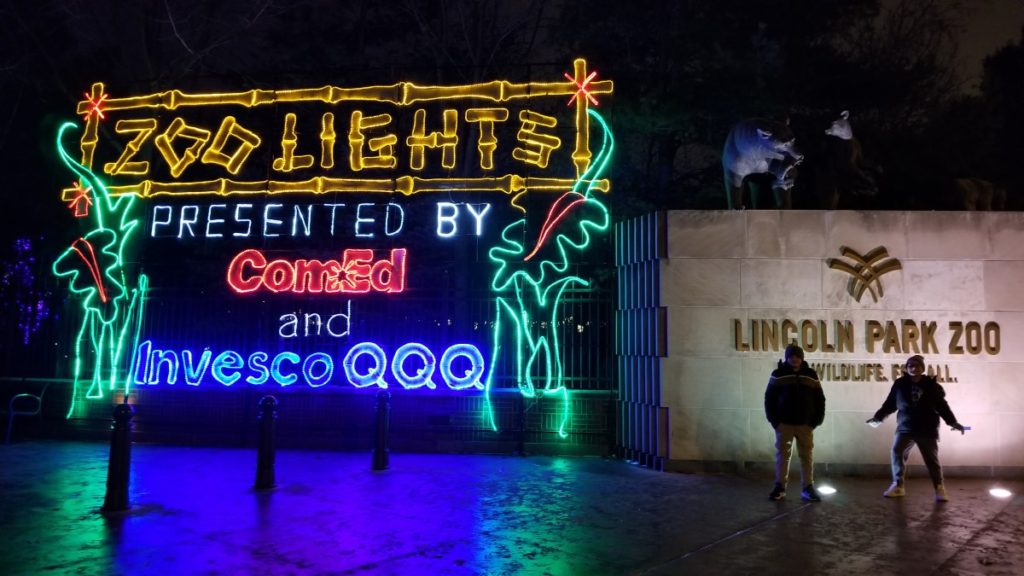 Christmas in Chicago 2022 should include a visit to Lincoln Park ZooLights. Pictured is the ZooLights sign presented by ComEd and InvescoQQQ lit up in front of the zoo.