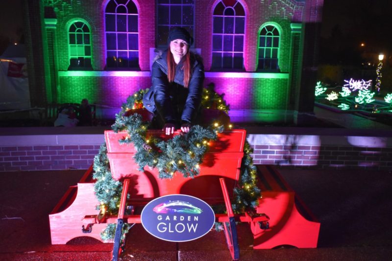 The Garden Glow STL sign with a wreath lit up with Christmas lights. 