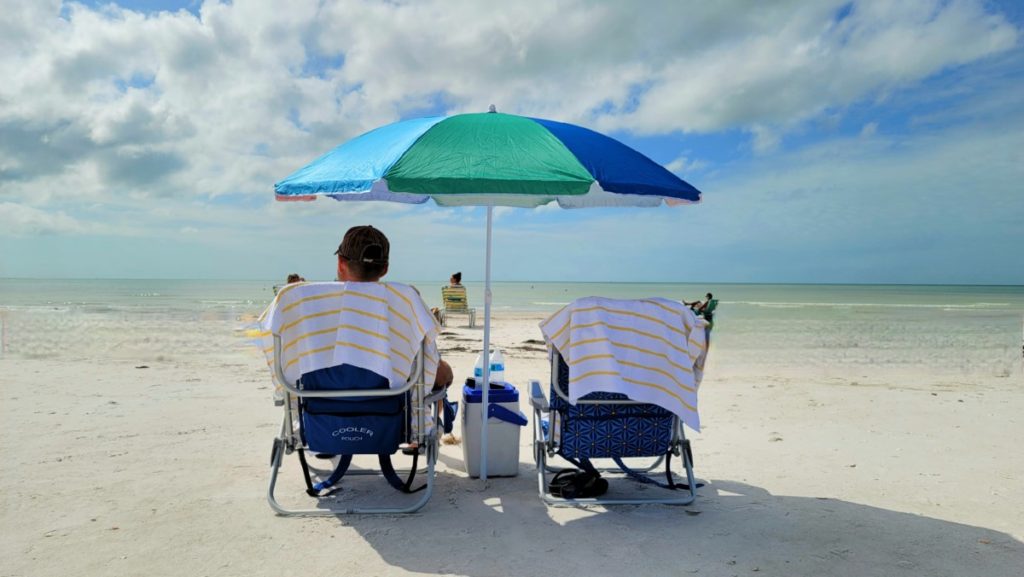 Two low beach chairs on white sand looking at the ocean.