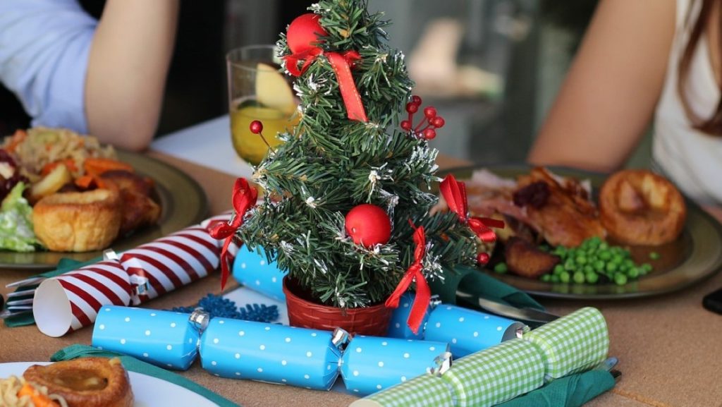 A festive dinner table with a small Christmas tree and three meals.