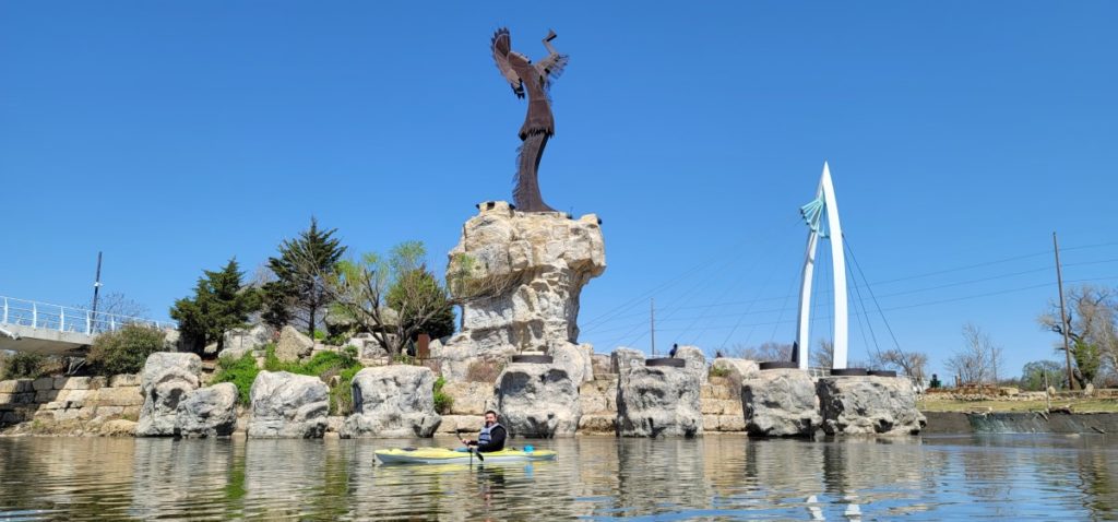 Kayaker below the Keeper of the Plains statue on the Arkansas River
