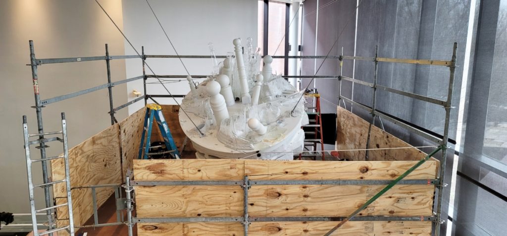 A white wood and glass sculpture still being worked on.