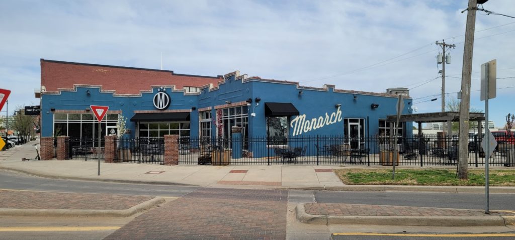 The outside of The Monarch, a blue painted brick building with an outdoor patio.