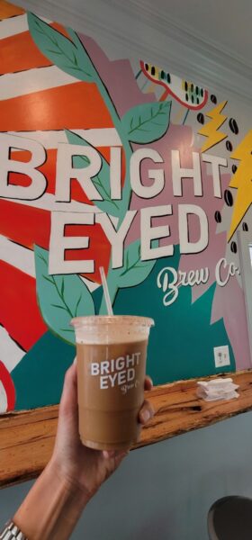 A cold coffee in front of the Bright-Eyed Brew Co mural in downtown Ocean Springs MS