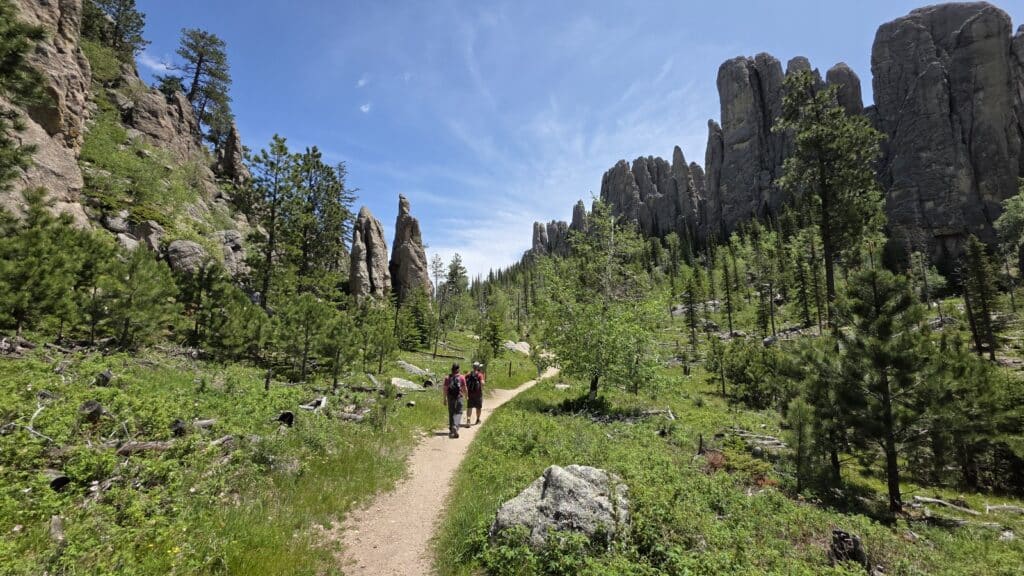 Two hikers walking among large granite pillars.