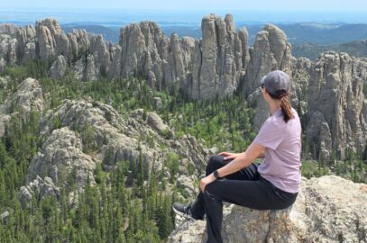 A woman hiker looking out at a rocky spire outcropping.