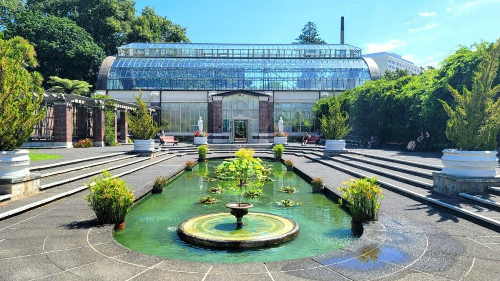 A Victorian-style glasshouse at Auckland Wintergardens facing a sunken pool.
